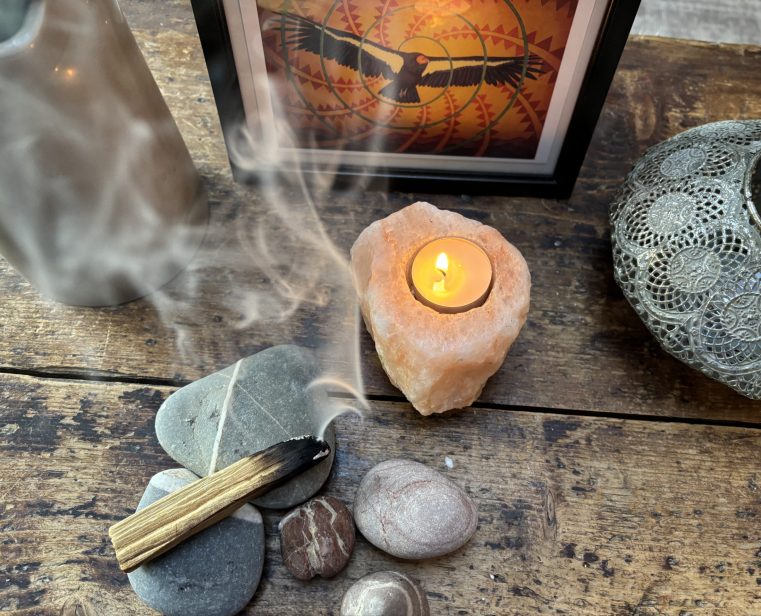Lit candle surrounded by stones and incense smoke