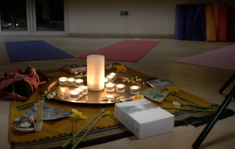 Candles and ritual items arranged on yoga mats indoors.