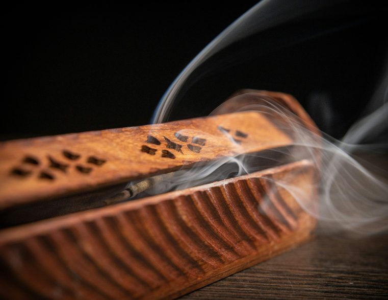 Incense smoke rising from a wooden incense holder